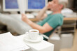 Businessman reading paperwork in office behind coffee cup