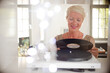 Older woman playing vinyl record on turntable