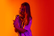 © Lustre Art Group  - Cropped portrait of young beautiful caucasian girl expressively singing with microphone on gradient yellow red background