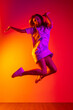 © Lustre Art Group  - Joyfully jumping. Full-length portrait of young beautiful girl in motion isolated on colorful yellow pink red background in neon