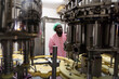 © amorn - Controller worker working checking automated conveyor belt at beverage factory. African American male engineer worker working or maintenance with the machine in the industrial factory
