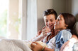 © KOTO - Teenage couple lying in bed and eating popcorn