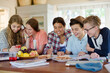 © KOTO - Group of smiling teenagers gathered around table in dining room