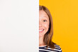 © deagreez - Portrait of charming positive young lady covering half face empty space wall isolated on yellow color background