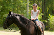 The girl sits astride a horse. A little girl (eight years old) sits astride a horse