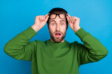 Poster - Photo of amazed young crazy shocked male raise glasses hear unexpected bad news isolated on blue color background