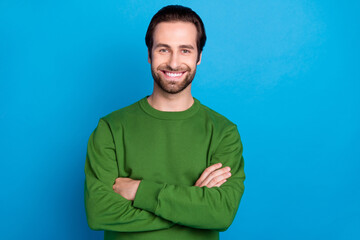 Sticker - Photo of young smiling cool businessman with folded arms wear green pullover isolated on vivid blue color background