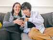 Brother and sister sitting on sofa and using smart phone