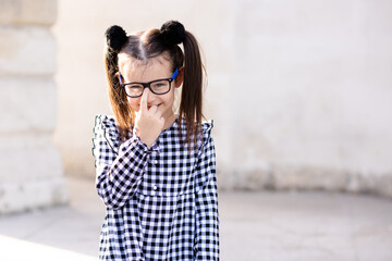 Wall Mural - Cute little pupil girl 5-6 year old wear glasses and casual stylish dress. Back to school. Childhood. Sweet toddler having fun outdoors. Looking at camera.