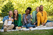 © PhotoAlto - Portrait of smiling young friends having picnic in public park
