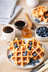 Wall Mural - Breakfast waffles with blueberries, honey and coffee served on a wooden table