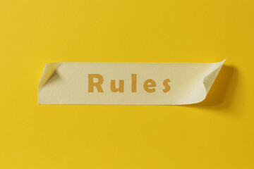 Word Rules written on piece of masking tape stuck to yellow background.