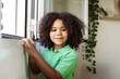 © PintoArt - an afro american boy with afro hair in the window of his house