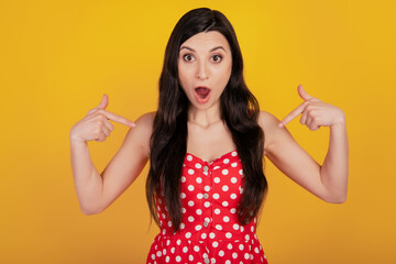 Portrait of shocked excited woman direct finger herself omg reaction wear dotted red dress on yellow background