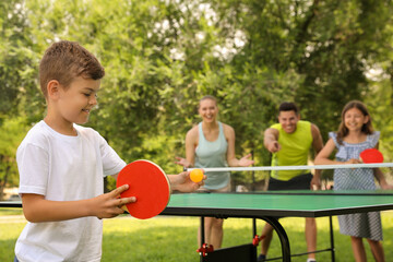 Happy family playing ping pong in park