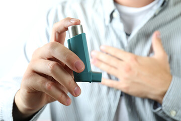 Wall Mural - Young man holds asthma inhaler during asthma attack