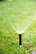Irigate, sprinkler head dispersing water on grass
