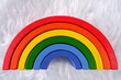 Wooden colorful toy rainbow on a white fur background,similar to an imitation of a cloud.Montessori concept,autism, environmental toys,art therapy, kindergarten, playroom,rainbow party,LGBT community