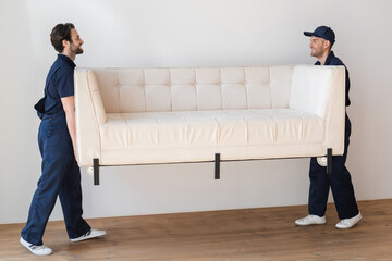 Wall Mural - side view of smiling workers lifting white sofa in apartment