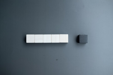 Wall Mural - Arranging a row of five white blank wooden blocks and one black blank wooden block.