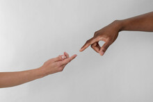 Woman and African American man touching fingers on light grey background, closeup
