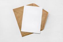 An Envelope Made Of Kraft Paper And A White Blank Card On A White Table. Blank Or Empty Postcard.