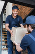© LIGHTFIELD STUDIOS - smiling mover carrying carton box with blurred colleague while walking upstairs
