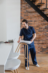 Wall Mural - smiling worker holding stool near wires on white kitchen table