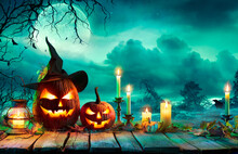 Halloween At Night - Pumpkins With Witch Hat And Candles On Table In Mystery Landscape
