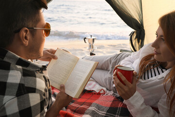 Wall Mural - Couple resting in camping tent near sea