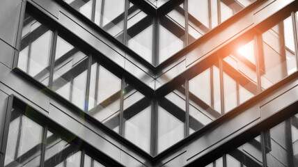 Modern architectural details. Modern glass facade with a geometric pattern. Contemporary corporate business architecture. Red sun on horizon. Black and white toned image.