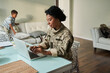 © Yakobchuk Olena - Black woman soldier using laptop at table