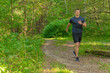 © Ilya - A man athlete runs in the park outdoors, around the forest, oak trees green grass young enduring athletic athlete exercise, fitness jogger motion, trees man. Summer leisure running, feet stretches