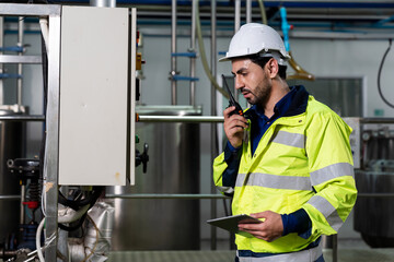 Technicians male worker working with digital tablet. Engineering male worker repairing, maintenance and checking the operation of equipment in the industrial factory, wearing safety uniform and helmet