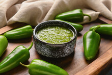 Bowl Of Tomatillo Salsa Verde Sauce And Jalapeno Pepper On Table