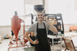 © F8  \ Suport Ukraine - Portrait of handsome modern man wearing apron talk phone while standing at coffee roasting machine at factory