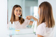 © Syda Productions - dental care, hygiene and people concept - happy smiling teenage girl with electric toothbrush brushing teeth at bathroom