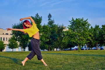 Wall Mural - beautiful young girl with pink hair, yellow tank top trains stretching in park