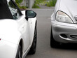 © 編集部 MOBY - 狭い道ですれ違う2台のスポーツカーとコンパクトカー (Two cars passing each other on a narrow street, a sports car and a compact car.)