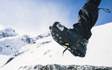 Crampons and shoes walking on ice and snow during outdoor winter trekking. Close up.