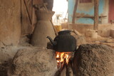 Fototapeta Do akwarium - horizontal closeup photography of an old black kettle, standing over yellow and orange fire flames, on three stones, outdoor on a sunny day in the gambia, Africa