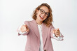 © Cookie Studio - Business and corporate people concept. Happy blond woman entrepreneur in glasses and suit, pointing fingers at camera and smiling, congratulating you, white background