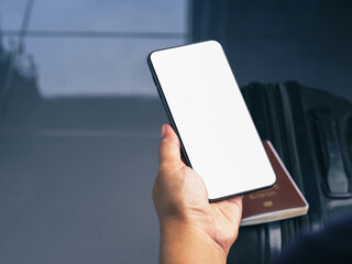 Wall Mural - hand holding of a smartphone with suitcase background. close-up photo. space for text. technology, c