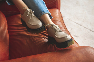 Wall Mural - Luxurious photo of casual sneakers on teen girl sitting on old and retro armchair, studio shot photo