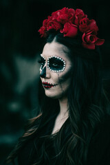 Wall Mural - Vertical shot of a woman with Halloween makeup and a flower crown, in a spooky forest