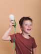 © ADDICTIVE STOCK - Smiling boy with decorative light bulb on beige background