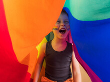 Excited Boy With Striped Makeup Screaming Under Rainbow Flag