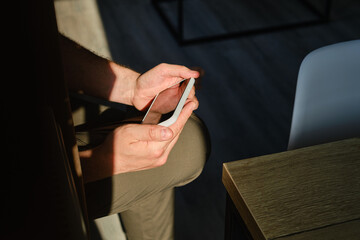 Wall Mural - man holds a phone in his hands and plays and he is happy with the result. a young man sits on the co