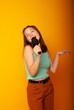 © Marina Chernivetskay - girl brunette teenager, 15 years holding a microphone in his hands depicting singing with his mouth open. The concept of postcards or a vocal lesson at school, back to school