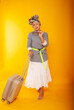 © Marina Chernivetskay - a woman with a suitcase on a yellow background in isolation. Traveler